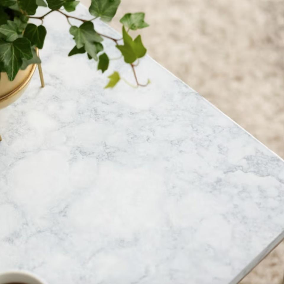 the marble contact paper on the corner of a table with a plant and coffee cup