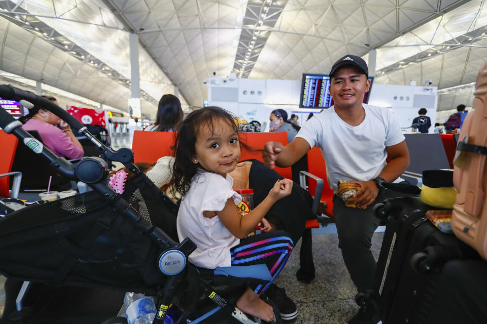 周五在機場，菲律賓旅客Andres和女兒返回菲律賓的航班被取消，二人正等待重新安排航班。 (AP Photo/Daniel Ceng)