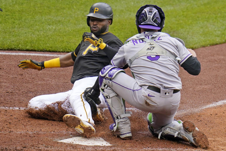 Gregory Polanco de los Piratas, izquierda, se adelanta al toque del receptor de los Rockies Dom Nunez y anota en la quinta entrada del primer partido de una doble jornada en Pittsburgh, sábado 29 de mayo de 2021. (AP Foto/Gene J. Puskar)