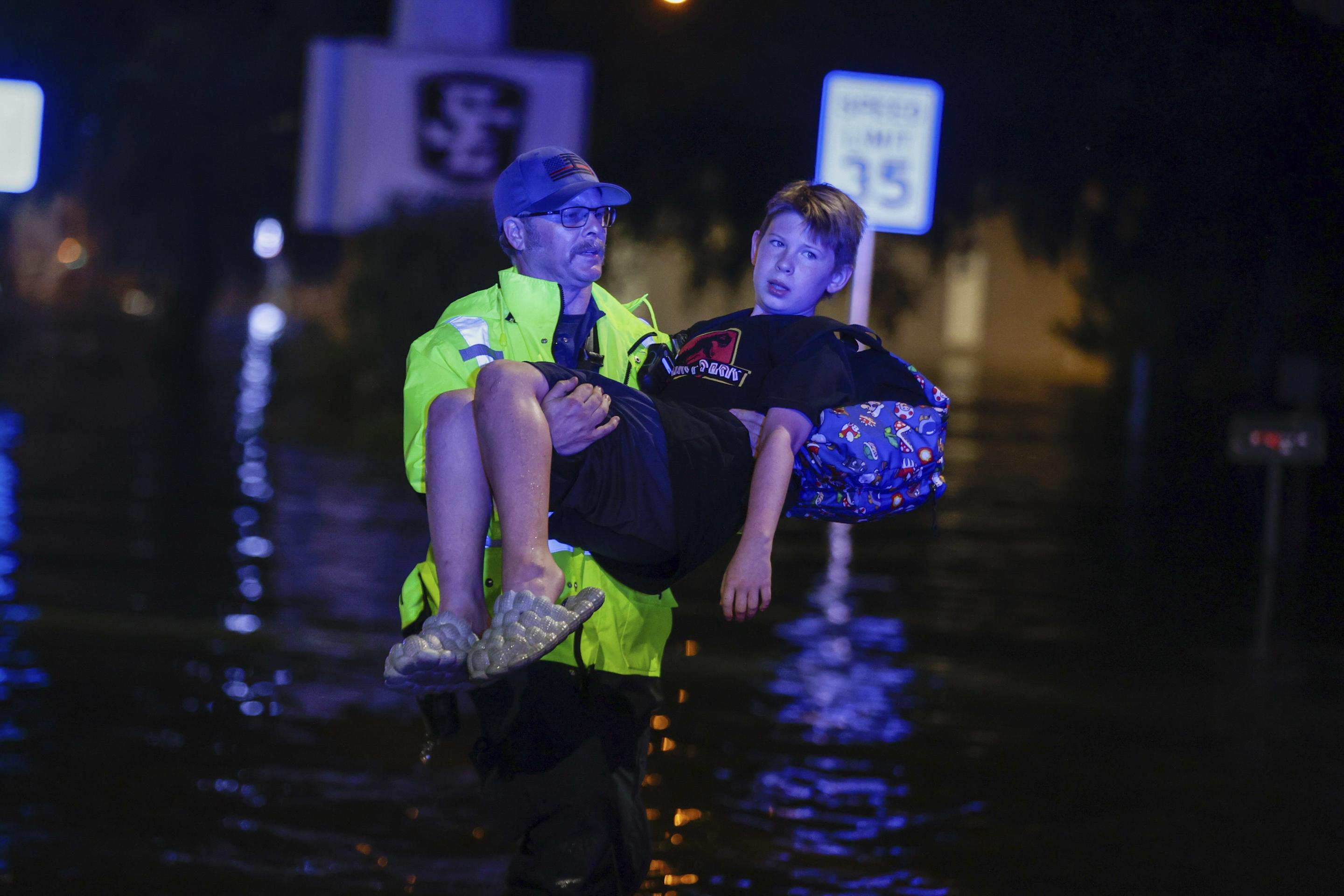 A Citrus County firefighter carries 11-year-old Michael Cribbins while conducting flood rescue operations following Hurricane Helene in Crystal River, Florida, on Friday.