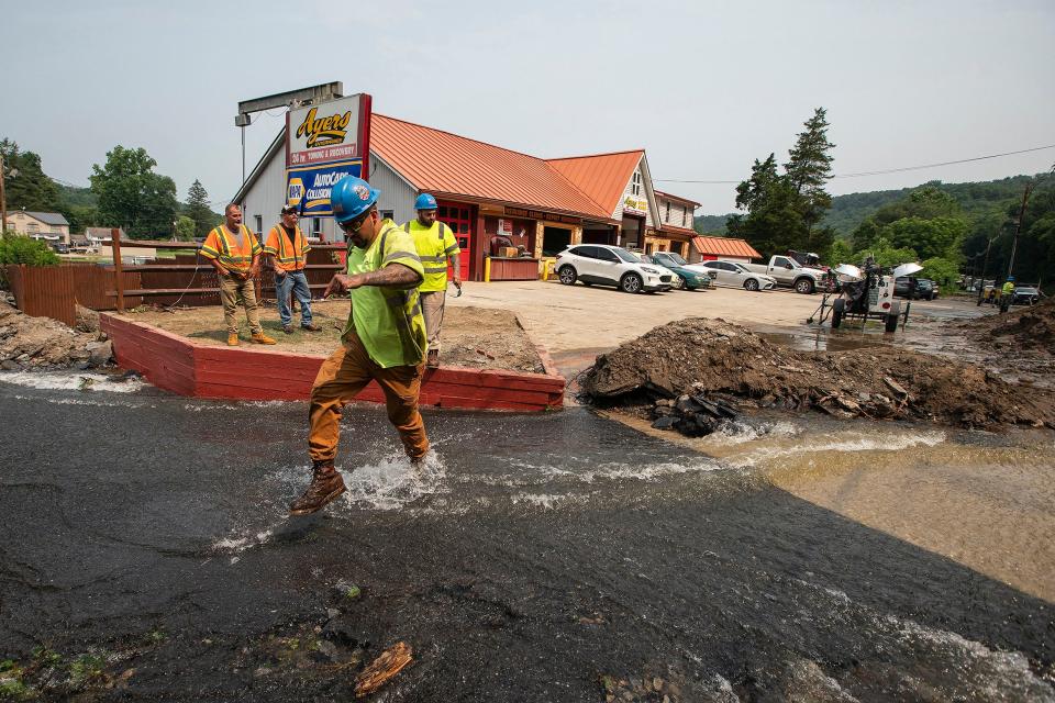 Workers cross roadway impacted by recent storms and flooding, Monday, July 17, 2023, in Belvidere, New Jersey. (AP Photo/Eduardo Munoz Alvarez)