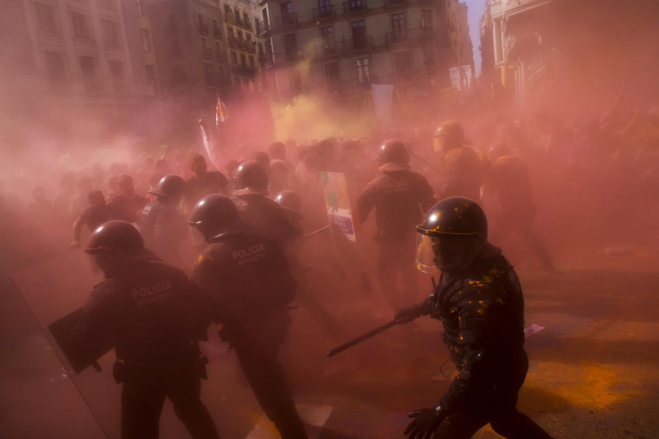 Catalan police officers clash with pro independence demonstrators on their way to meet demonstrations by member and supporters of National Police and Guardia Civil, as coloured powder is seen in the air after being thrown by protesters, in Barcelona on Saturday, Sept. 29, 2018. (AP Photo/Emilio Morenatti)