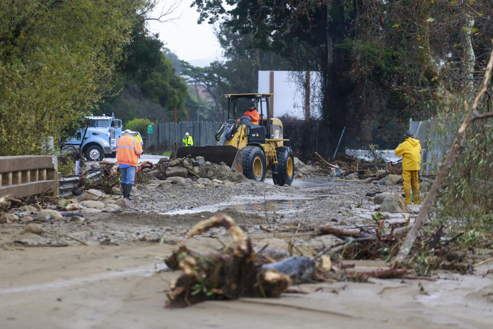 A work crew cleans up an area of Highway 101 that flooded in Montecito, Calif., Tuesday, Jan. 10, 2023. California saw little relief from drenching rains Tuesday as the latest in a relentless string of storms swamped roads, turned rivers into gushing flood zones and forced thousands of people to flee from towns with histories of deadly mudslides. (AP Photo/Ringo H.W. Chiu)