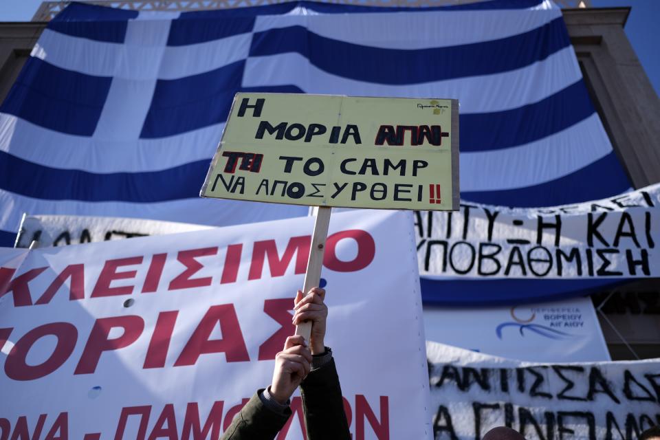 A protester holds a placard that reads "Moria demands the camp be withdrawn" outside the Municipality of Mytilene during a rally on the northeastern Aegean island of Lesbos, Greece, on Wednesday, Jan. 22, 2020. Local residents and business owners have launched a day of protest on the Greek islands hardest hit by migration, demanding the Greek government ease severe overcrowding at refugee camps. (AP Photo/Aggelos Barai)