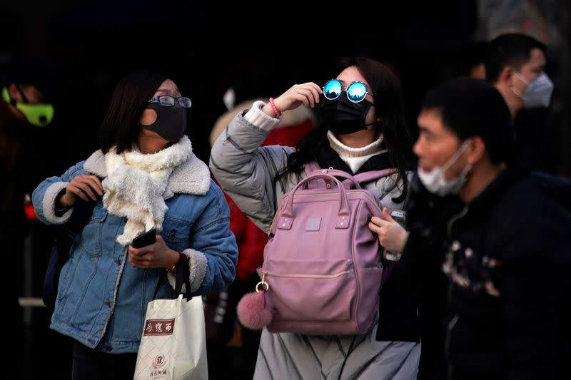 Passengers wearing masks walk outside the Shanghai railway station in Shanghai