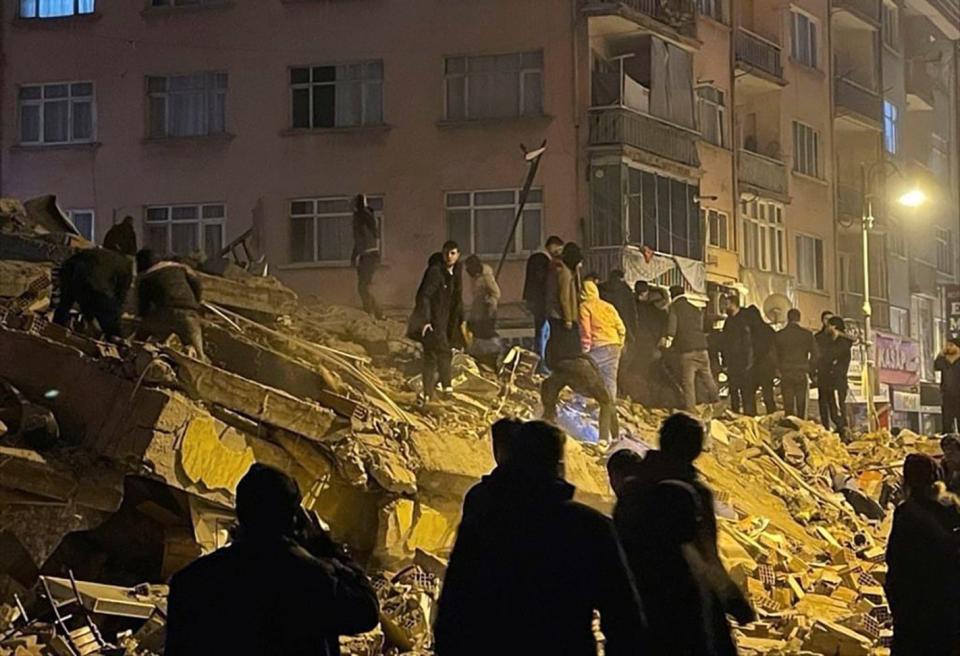 People try to reach trapped residents in a collapsed building in Pazarcik, in Kahramanmaras province, southern Turkey, early Monday, Feb. 6, 2023. 
