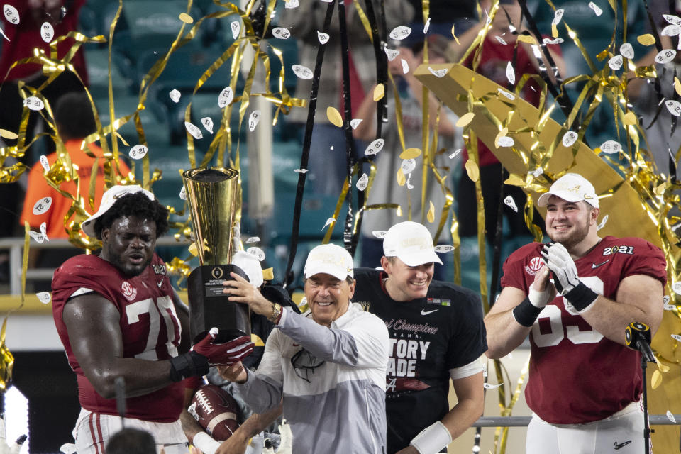 MIAMI GARDENS, FL - JANUARY 11: Alabama Crimson Tide offensive lineman Alex Leatherwood (70) and Alabama Crimson Tide head coach Nick Saban hold the trophy as they celebrate on the stage with Alabama Crimson Tide quarterback Mac Jones (10), Alabama Crimson Tide wide receiver DeVonta Smith (6), Alabama Crimson Tide offensive lineman Landon Dickerson (69) and Alabama Crimson Tide defensive lineman Christian Barmore (58) after the Alabama Crimson Tide defeated the Ohio State Buckeyes at the College Football Playoff National Championship football game on January 11, 2021 at the Hard Rock Stadium in Miami Gardens, FL. (Photo by Doug Murray/Icon Sportswire via Getty Images)