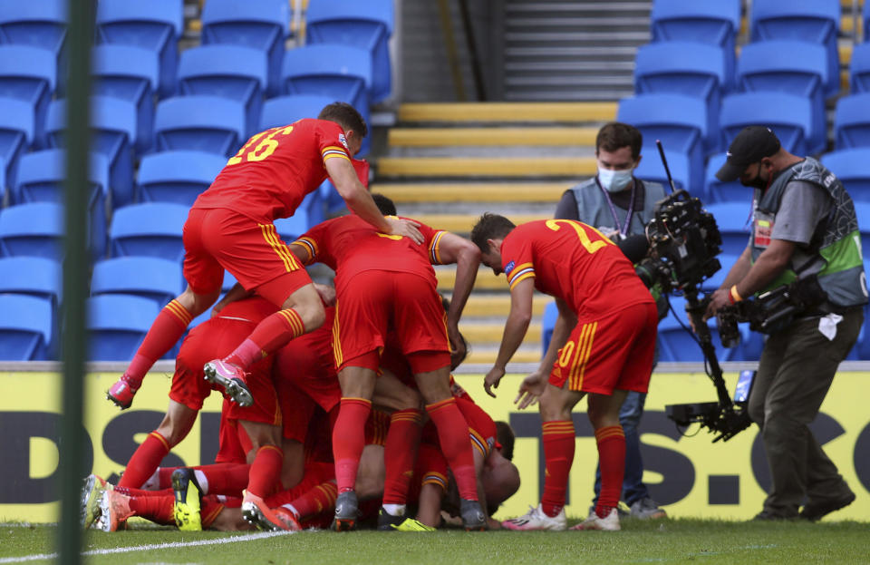 Wales' Neco Williams is mobbed by his team-mates as he celebrates scoring his side's first goal of the game against Bulgaria, during their UEFA Nations League Group 4 soccer match at Cardiff City Stadium in Cardiff, Wales, Sunday Sept. 6, 2020. (David Davies/PA via AP)