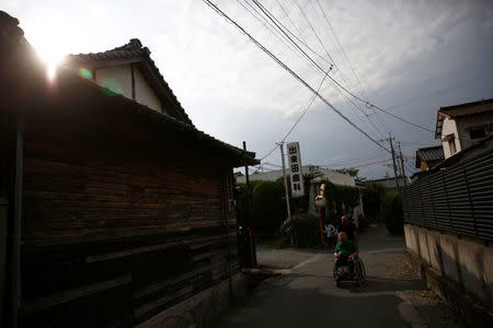 A caretaker pushes congenital Minamata disease patient Isamu Nagai in a wheelchair to take him to a group care home where Nagai lives, in Minamata, Kumamoto Prefecture, Japan, September 13, 2017. REUTERS/Kim Kyung-Hoon