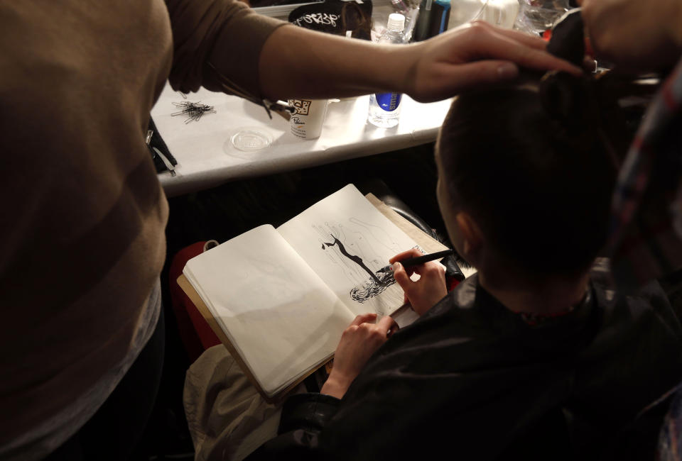 A model sketches while having her hair done backstage before the Nanette Lepore Fall 2013 collection show during Fashion Week, Wednesday, Feb. 13, 2013 in New York. (AP Photo/Jason DeCrow)