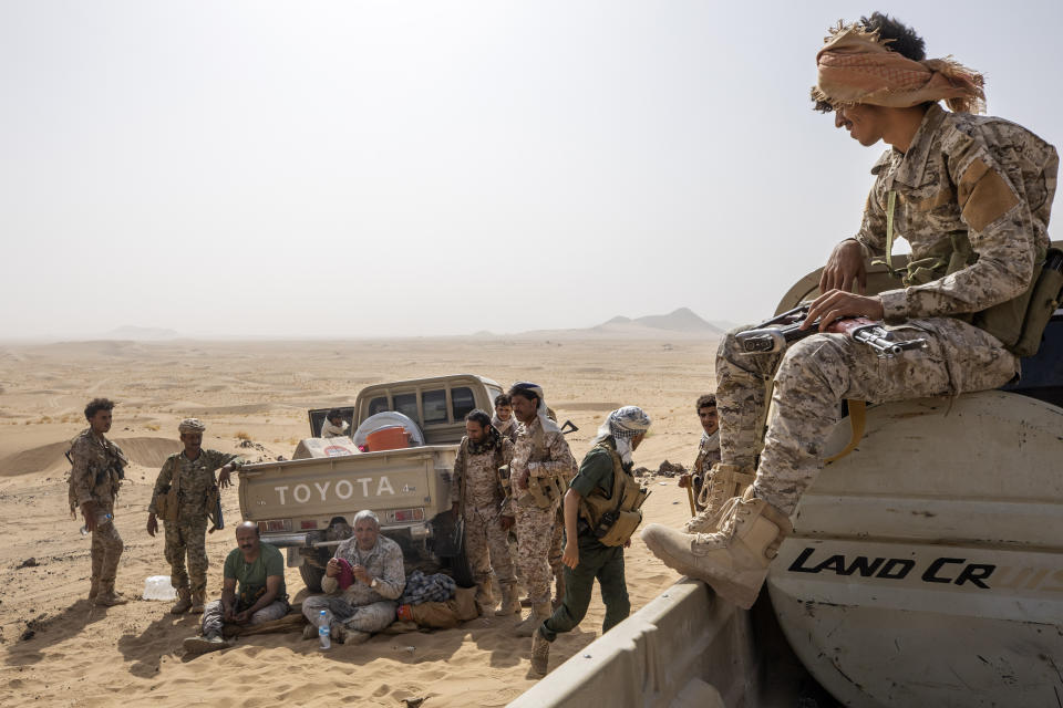 Maj. Gen. Nasser al-Dhaibani, who headed military operations of the government's armed forces, fourth from left, holds his beret as he rests with fighters backed by the Saudi-led coalition, near the Kassara frontline with Houthi fighters, near Marib, Yemen, June 20, 2021. On Monday, Dec. 13, 2021, officials said al-Dhaibani died in clashes between Yemeni government forces and the country's Houthi rebels. The development is a big blow to the forces of Yemen's internationally recognized government, who have been fighting for months against the Iranian-backed Houthis’ attempt to take Marib. (AP Photo/Nariman El-Mofty)