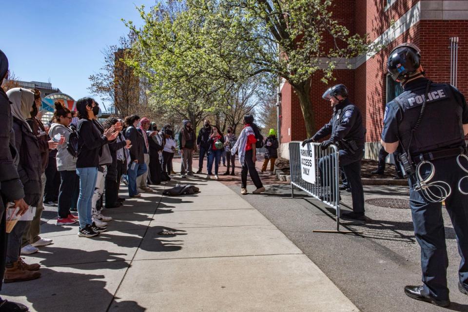 Pro-Palestinian protesters stand in front of a police barricade at Northeastern University on 27 April. Police arrested 29 students and six university employees (AFP via Getty Images)