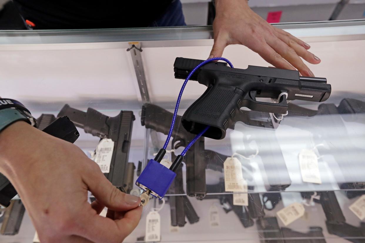 A firearms dealer demonstrates how a lock works on a handgun.