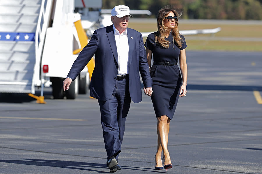 Melania Trump, wearing a navy blue dress, holds hands with her husband at Wilmington International Airport November 5, 2016