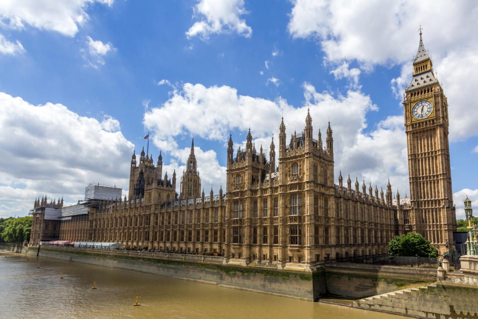 A view of Parliament from the river, with a flag flying over Westminster Abbey in the background.