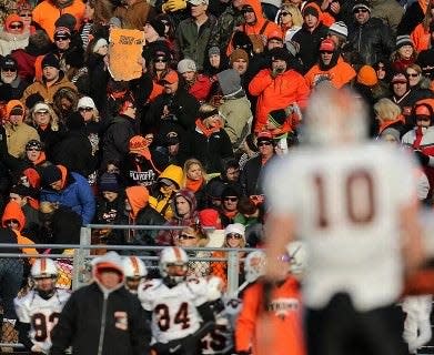 Washington QB Colton Marshall (10) watches while his father stands in the grandstand, holding an orange piece of debris from the QB's bedroom, destroyed by a tornado, turned into a sign that read "Touchdown" during a Nov. 23, 2013 playoff game at Sacred Heart-Griffin.