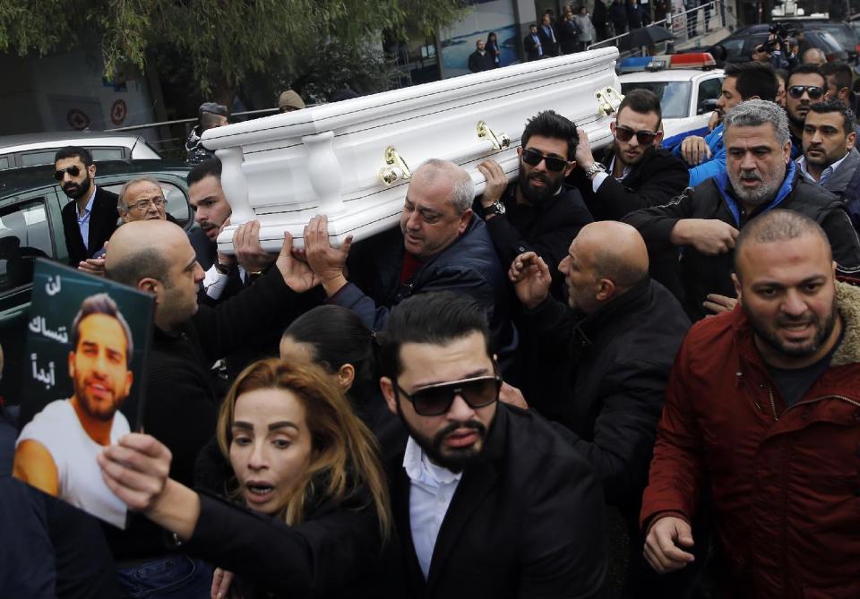 Relatives and friends of Elias Wardini, a Lebanese man who was killed in the New Year's Eve Istanbul nightclub attack, carry his coffin, as his sister, foreground, holds her brother's portrait, during his funeral, in Beirut, Lebanon, Tuesday, Jan. 3, 2017. The gunman killed 39 people, most of them foreigners, including three Lebanese citizens, at the Istanbul nightclub. Arabic on portrait at left reads, "We will not ever forget you." (AP Photo/Hussein Malla)