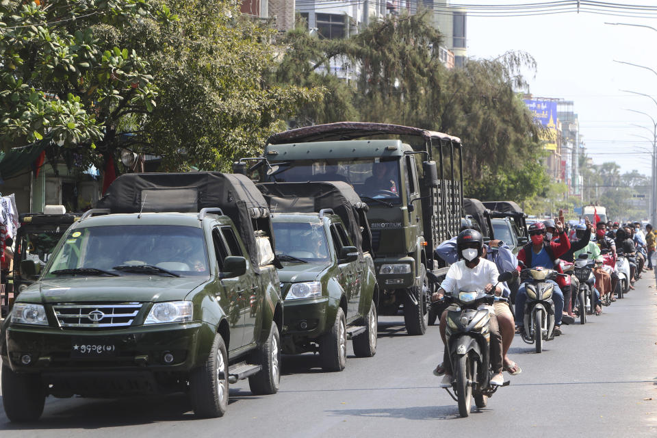 Anti-coup protesters flash the three-fingered salute as they drive their motorbikes past military vehicles in Mandalay, Myanmar on Monday, Feb. 15, 2021. Myanmar's military leaders extended their detention of Aung San Suu Kyi, whose remand was set to expire on Monday, as protests continued to roil the Southeast Asian country following a military coup earlier this month. (AP Photo)