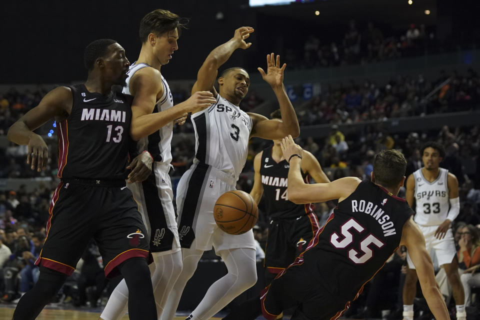 Miami Heat's Duncan Robinson, right, falls after fighting for control of the ball against San Antonio Spurs' Keldon Johnson, during the second half of an NBA basketball game, at the Mexico Arena in Mexico City, Saturday, Dec. 17, 2022. (AP Photo/Fernando Llano)