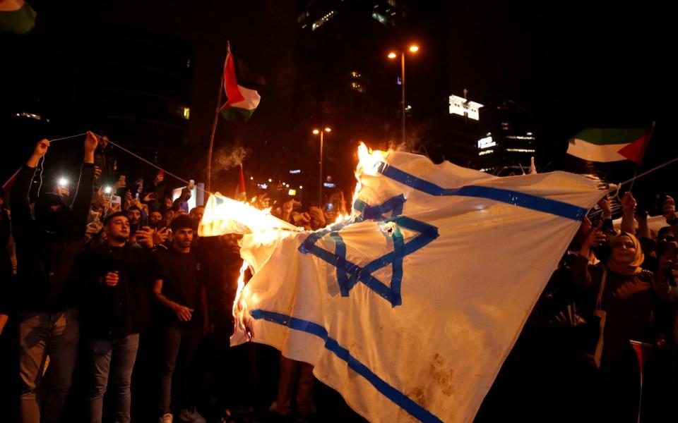 Demonstrators set fire to a makeshift Israeli flag during a protest, after hundreds of Palestinians were killed in a blast at Al-Ahli hospital in Gaza