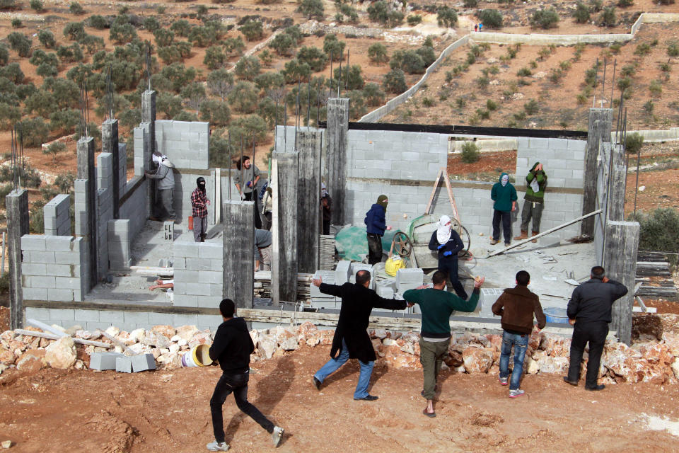 Palestinians from the village of Qusra (front) surround a group of Israeli settlers at a construction site, who sparked clashes after entering the village near Nablus, on January 7, 2014. (JAAFAR ASHTIYEH/AFP/Getty Images)