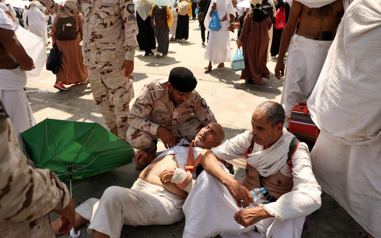 A man affected by the extreme heat is helped by a member of the Saudi security forces