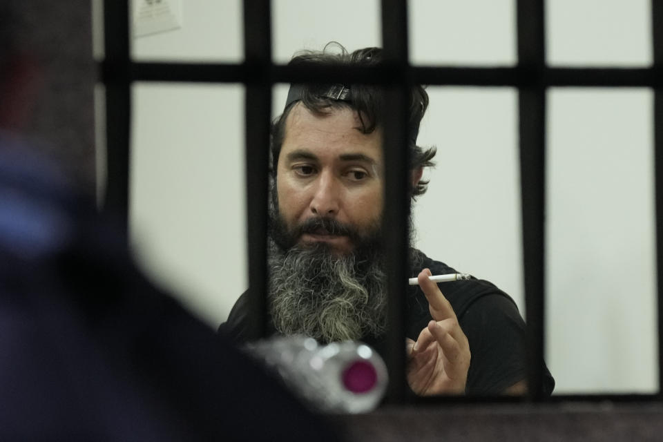 An armed man talks to hostages inside a bank in Beirut, Lebanon, Thursday, Aug. 11, 2022. A Lebanese security official says a man armed with a shotgun has broken into a Beirut bank, holding employees hostage and threatening to set himself ablaze with gasoline unless he receives his trapped saving. (AP Photo/Hussein Malla)