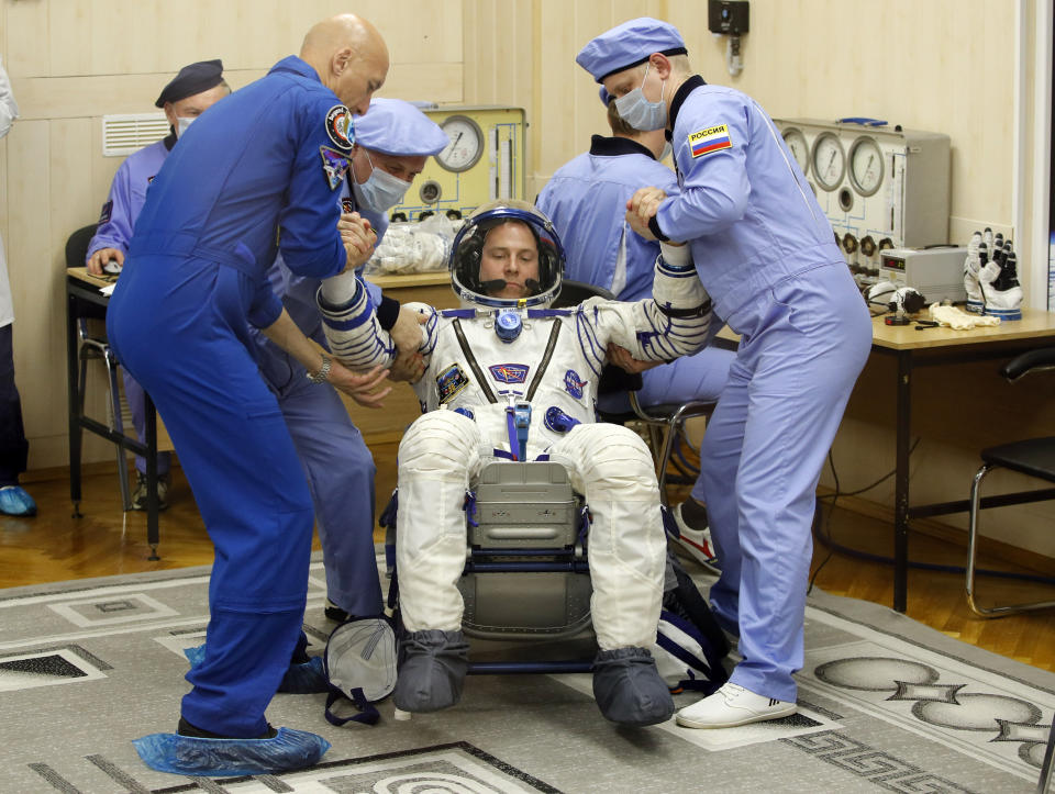Russian Space Agency experts help U.S. astronaut Nick Hague, member of the main crew of the expedition to the International Space Station (ISS), to stand up after inspecting his space suit prior the launch of Soyuz MS-12 space ship at the Russian leased Baikonur cosmodrome, Kazakhstan, Thursday, March 14, 2019. (AP Photo/Dmitri Lovetsky)