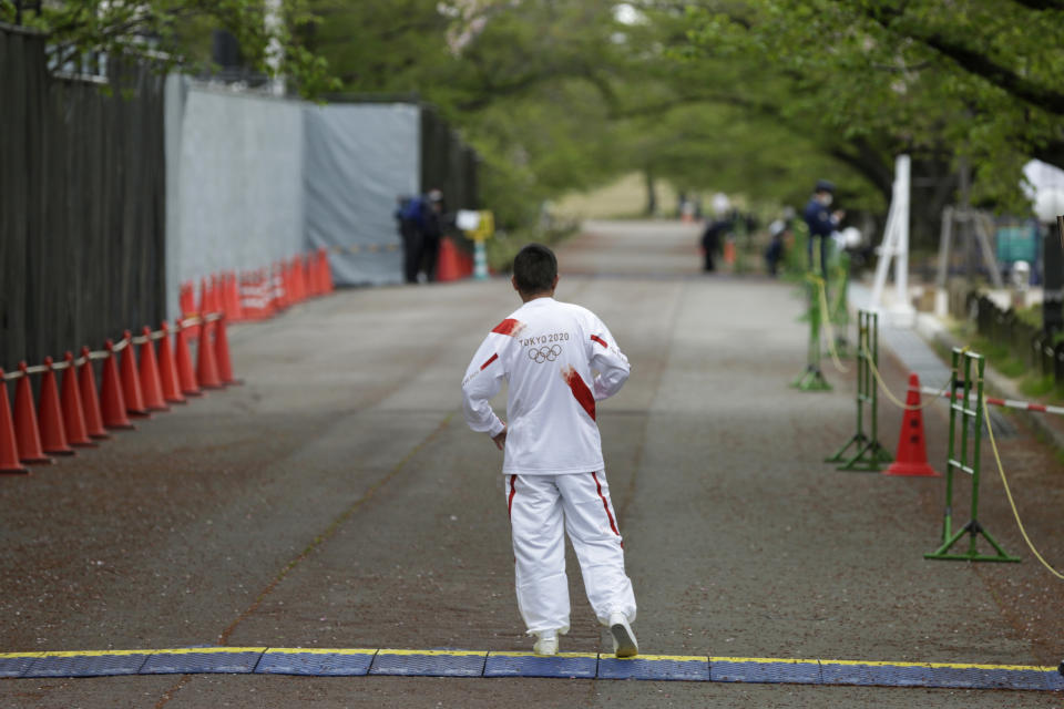 Entertainer Katsura Bunshi IV, participating as an Olympic torch relay runner, waits for his preceding runner during the first day of the Osaka round at a former Expo site in Suita, north of Osaka, western Japan, Tuesday, April 13, 2021. The heavily sponsored torch relay with 10,000 runners crisscrossing Japan also presents hazards. Legs scheduled for Osaka this week were pulled from the streets because of surging COVID-19 cases and relocated into a city park - with no fans allowed. Other legs across Japan are also sure to be disrupted. (AP Photo/Hiro Komae)