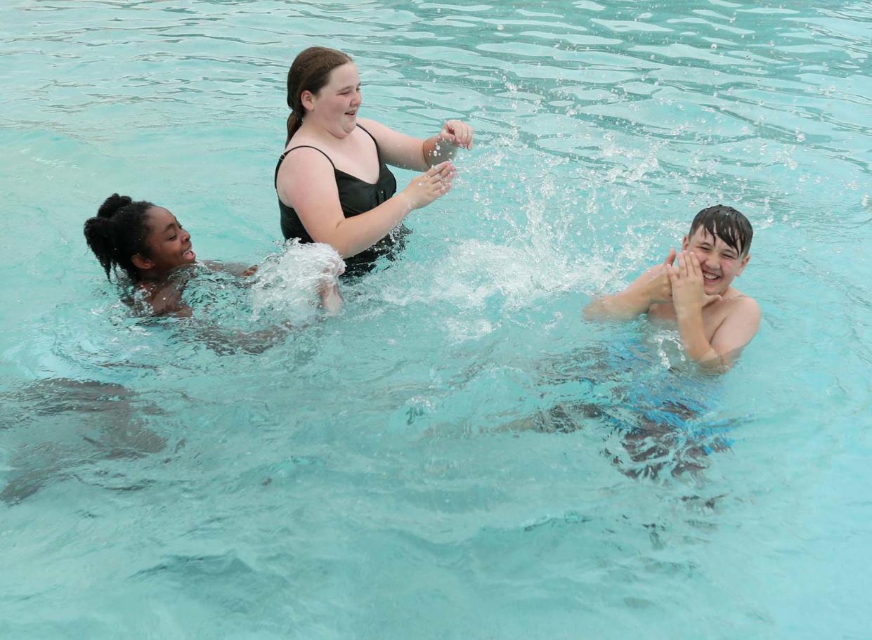 Sophia Riddle, 11, left, and her friend Madison Mounts, 12, splash Madison's brother Mason, 9, in the pool at Water Works Park Tuesday in Cuyahoga Falls.