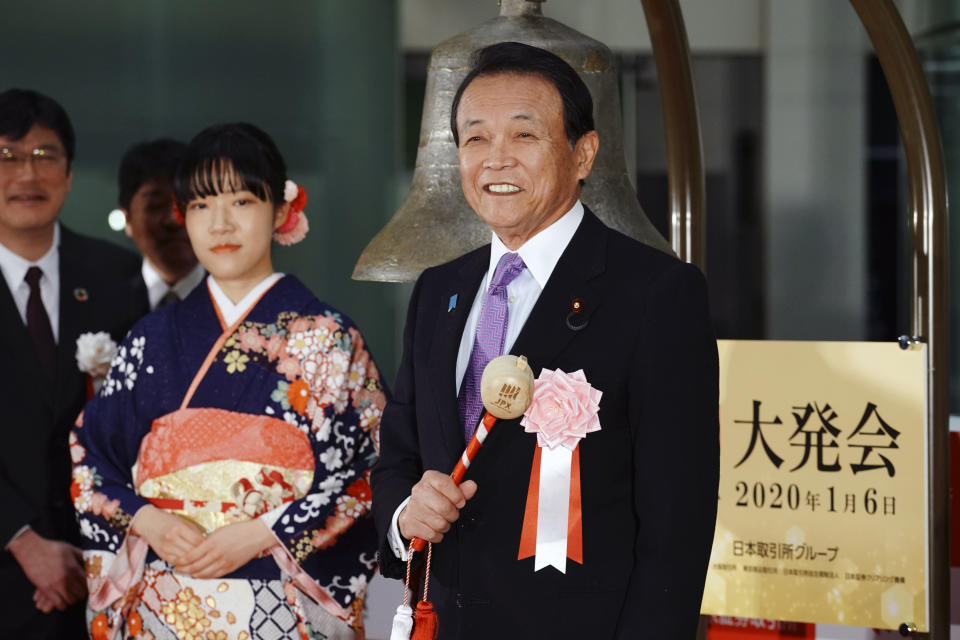 Japan's Finance Minister Taro Aso, right, poses before tolling a bell during a ceremony marking the start of this year's trading in Tokyo Monday, Jan. 6, 2020, in Tokyo. (AP Photo/Eugene Hoshiko)