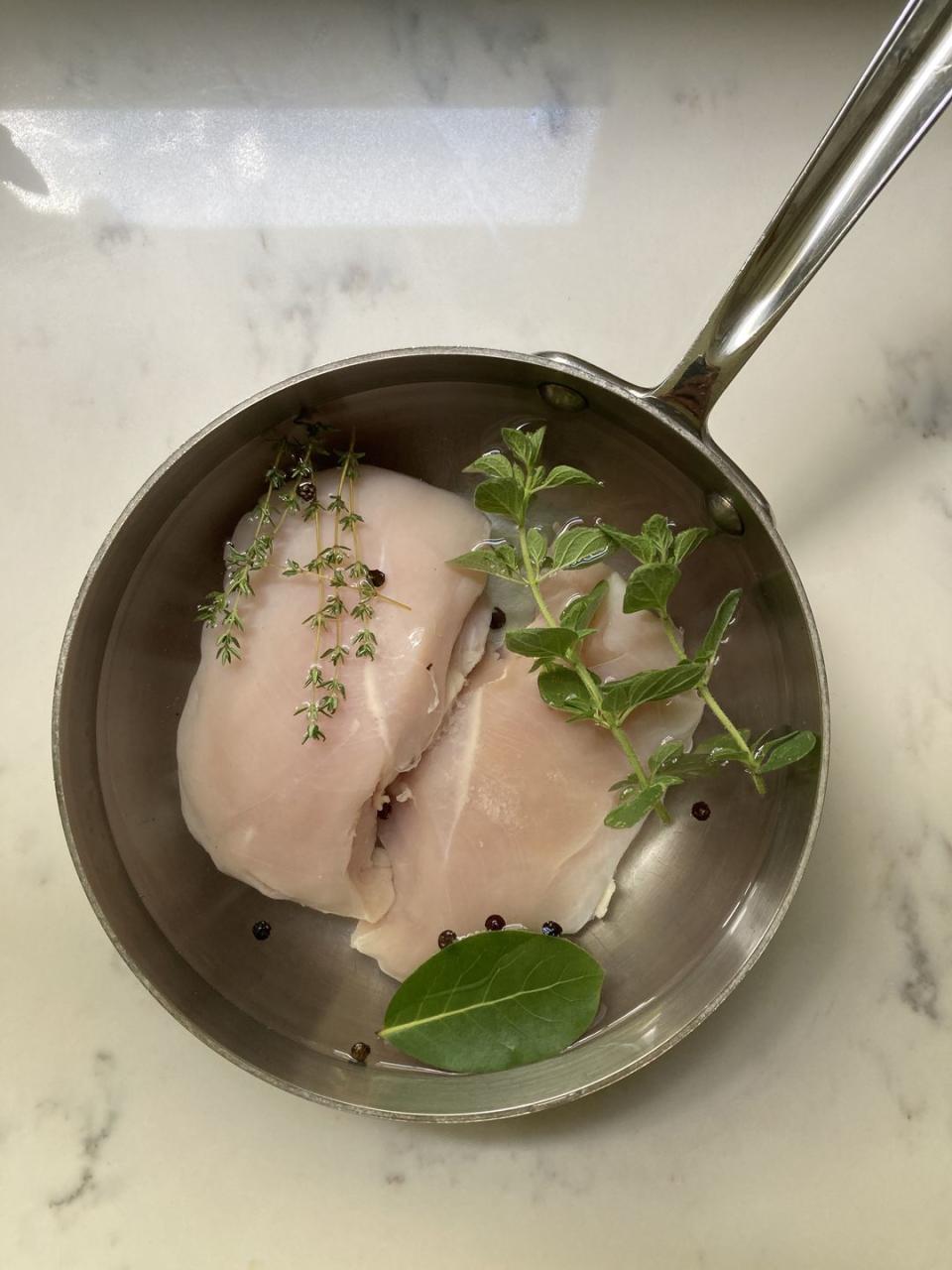 uncooked chicken in a pot with herbs and spices