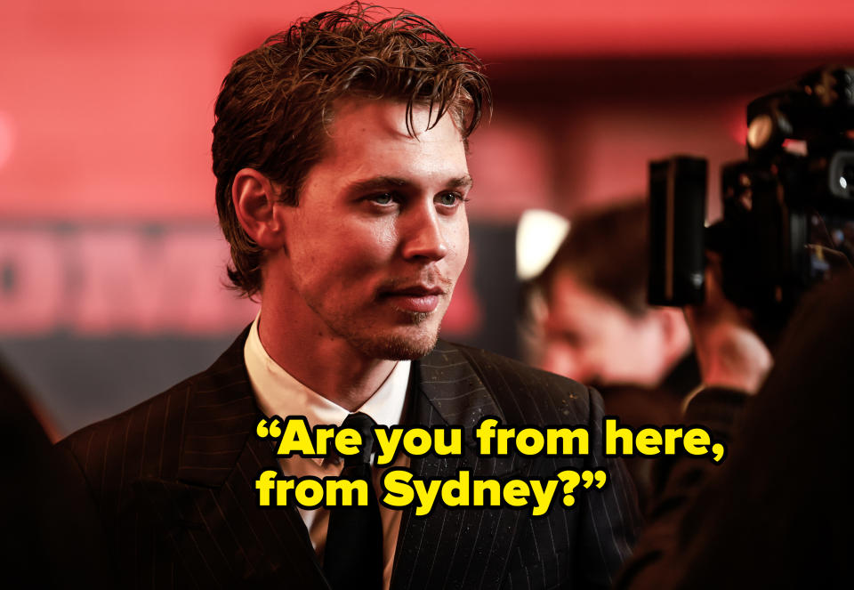 Austin Butler on the red carpet, wearing a pinstripe suit and tie, facing a camera for an interview