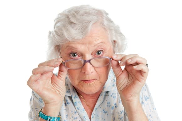 white-haired senior woman peering over her glasses with interest