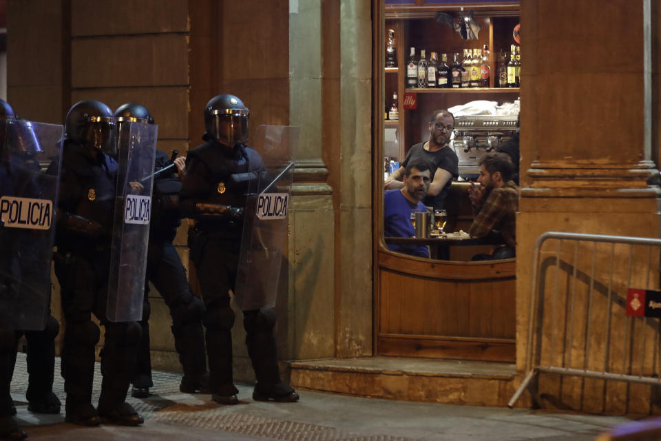 People sitting in a bar look at a line of policemen outside during a pro-independence demonstration in Barcelona, Spain, Sunday, Oct. 20, 2019. Barcelona and the rest of the restive Spanish region of Catalonia are reeling from several days of violent protests for the sentencing of 12 separatist leaders to lengthy prison sentences.Riots have broken out at nightfall following huge peaceful protests each day since Monday's Supreme Court verdict. (AP Photo/Ben Curtis)