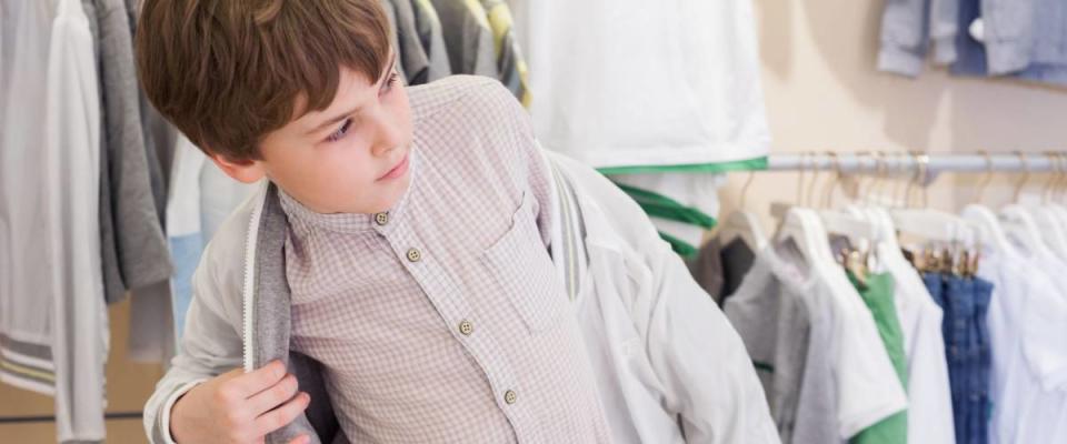 The boy tries on clothes in the childrens clothing store