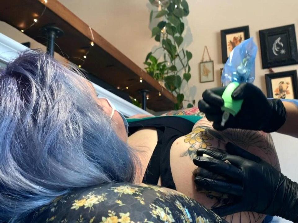 Client Katie Beach being tattooed at Hemlock Tattoo Studio in Calgary&#39;s Victoria Park. (Jennifer Dorozio/CBC - image credit)