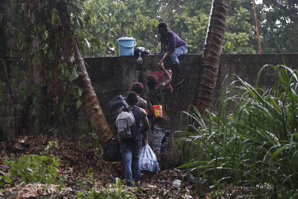 In this May 29, 2019 photo, Haitian migrants jump the wall of the Mesoamericana fairgrounds in Tapachula, Chiapas state, Mexico. As President Andrés Manuel López Obrador puts in motion a still-vague plan to crack down on migrants coming from Central America, observers fear an already overtaxed Mexico is woefully unprepared for the prospect of more arrests. (AP Photo/Marco Ugarte)