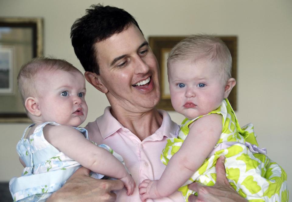 In this Tuesday, Aug. 20, 2013 photo, Trey Powell holds his six-month-old daughters Kylan, left, and Ashton in their home in Seattle. (AP Photo/Elaine Thompson)