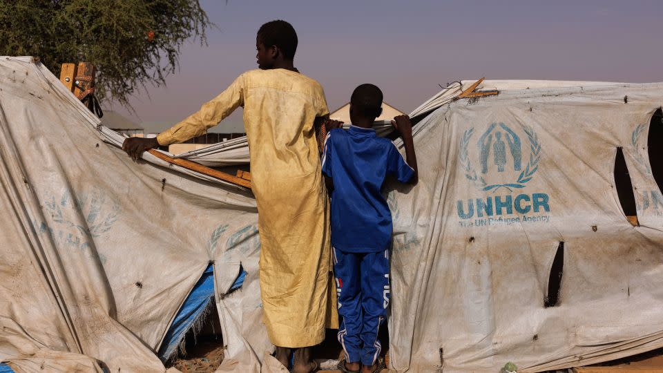Two boys peer over a UNHCR aid tent as newly arrived refugees from Darfur in Sudan, gather at a relocation camp near the border on April 19 in Adre, Chad. - Dan Kitwood/Getty Images
