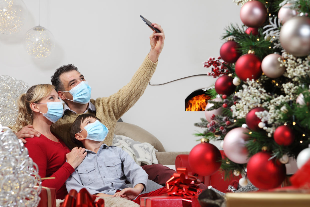 merry christmas, happy family wear surgical masks, forced to stay home alone because of the coronavirus, communicates with mobile phone remotely, christmas lockdown concept