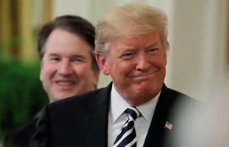 FILE PHOTO: U.S. President Donald Trump smiles next to U.S. Supreme Court Associate Justice Brett Kavanaugh as they participate in a ceremonial public swearing-in in the East Room of the White House in Washington