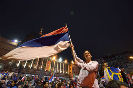 A supporter of Frente Amplio party waves the party flag as elected President Tabare Vazquez gives his speech in Montevideo after knowing the results of a runoff election, November 30, 2014. REUTERS/Carlos Pazos