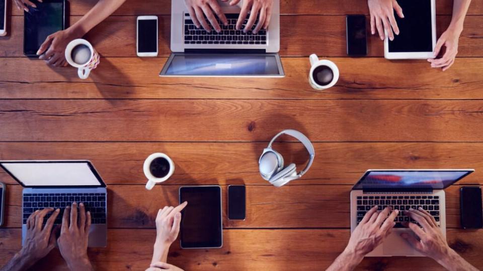 Overhead shot of young adults using technology at a table