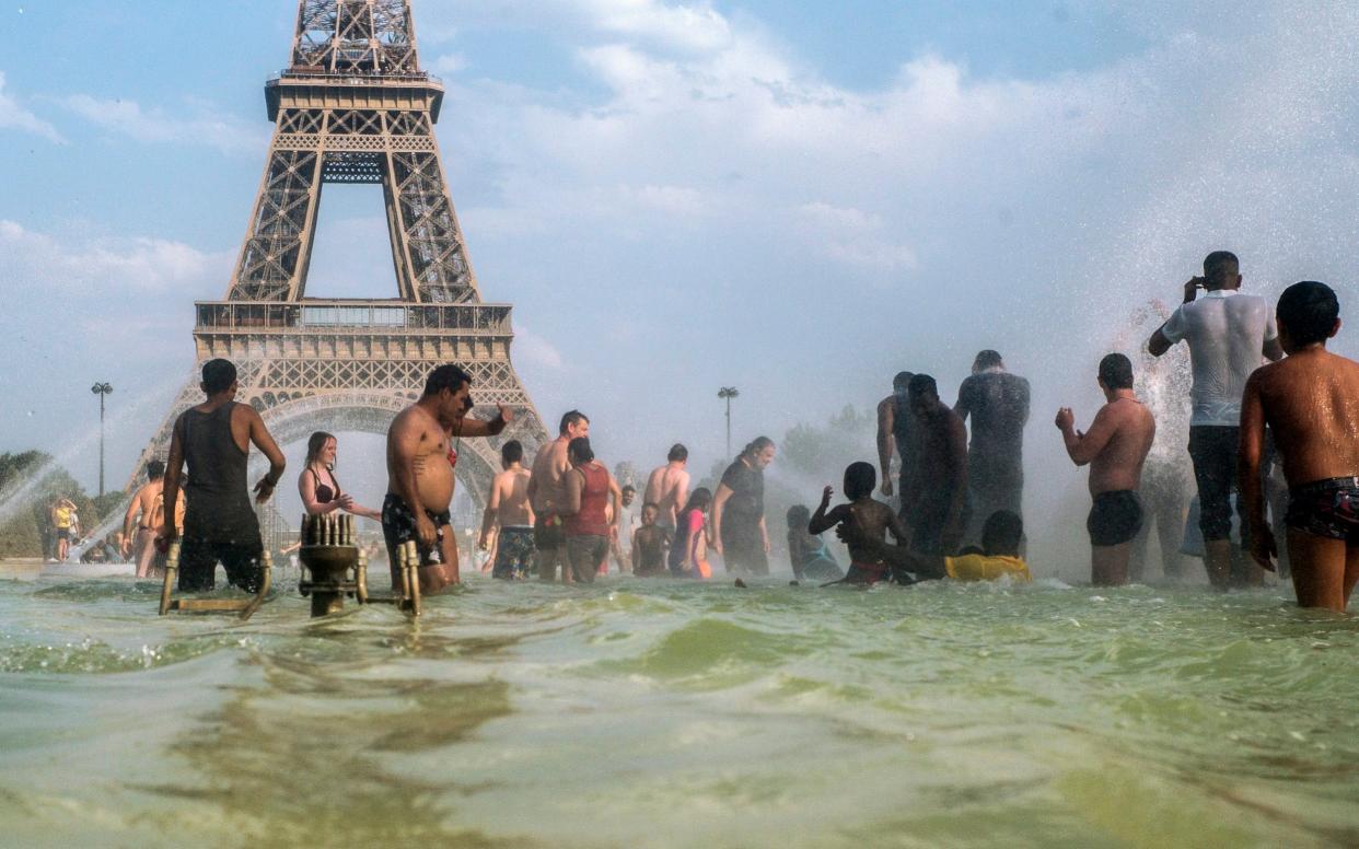 Parisians cool down in fountains near the Eiffel Tower on the day the city recorded its highest ever temperature - AP