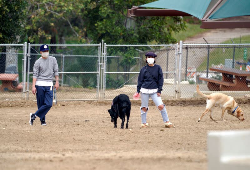 Dog owners wearing face masks watch their pets in the Silver Lake Dog Park during the outbreak of the coronavirus disease (COVID-19) in Los Angeles, California