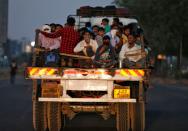 Migrant workers and their families travel in a trailer truck as they return to their villages during a 21-day nationwide lockdown to limit the spreading of Coronavirus disease (COVID-19), on the outskirts of Ahmedabad