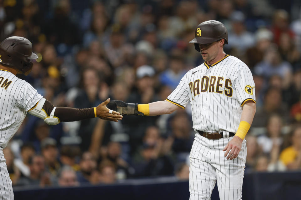 San Diego Padres' Jake Cronenworth, right, celebrates with Trent Grisham after scoring on a sacrifice fly by Austin Nola against the Pittsburgh Pirates during the second inning of a baseball game Saturday, May 28, 2022, in San Diego. (AP Photo/Mike McGinnis)