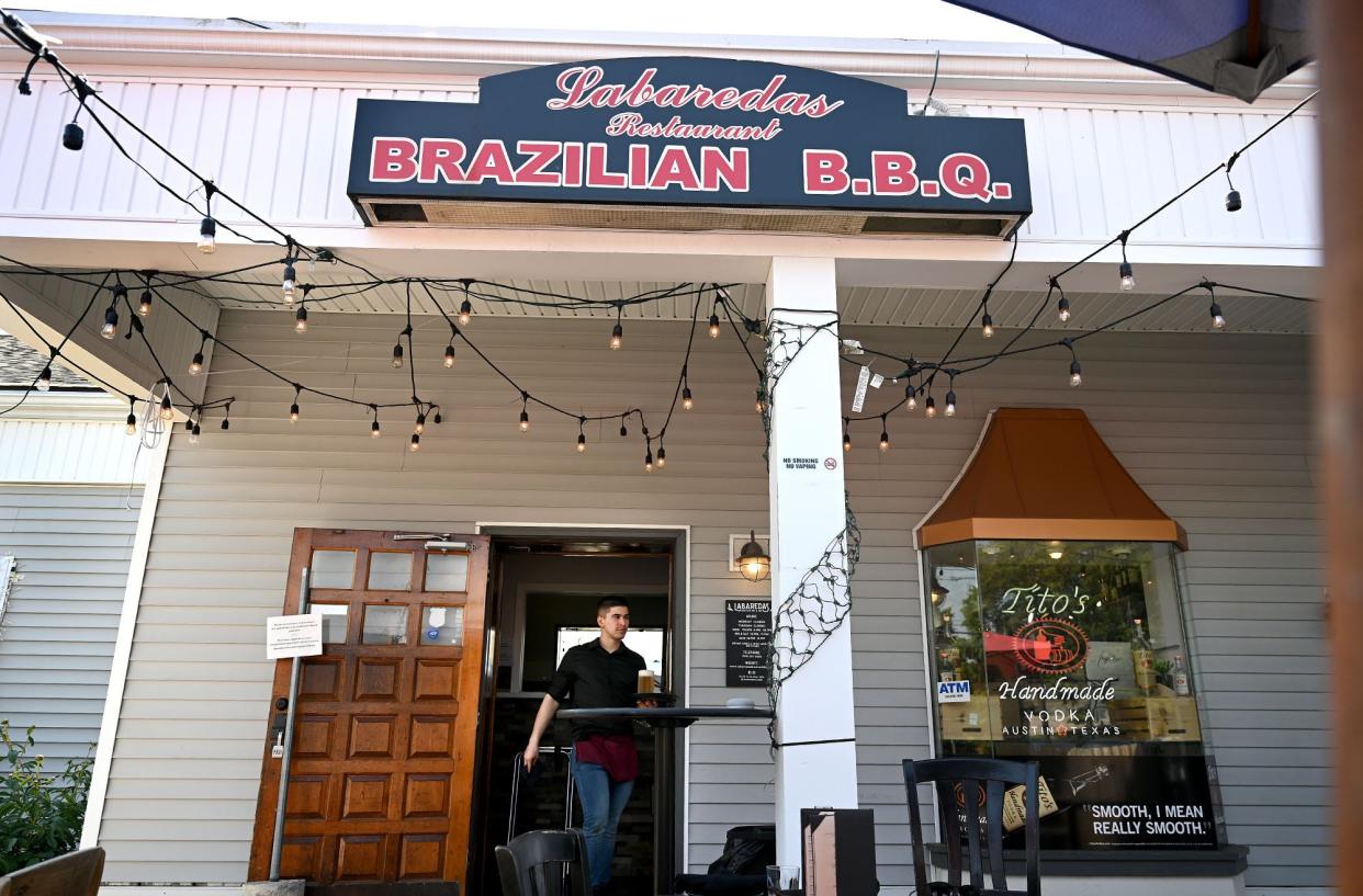 Waiter Anthony Viana carries a drink for an outdoor diner last May at Labaredas Brazilian BBQ & Bar in Marlborough.