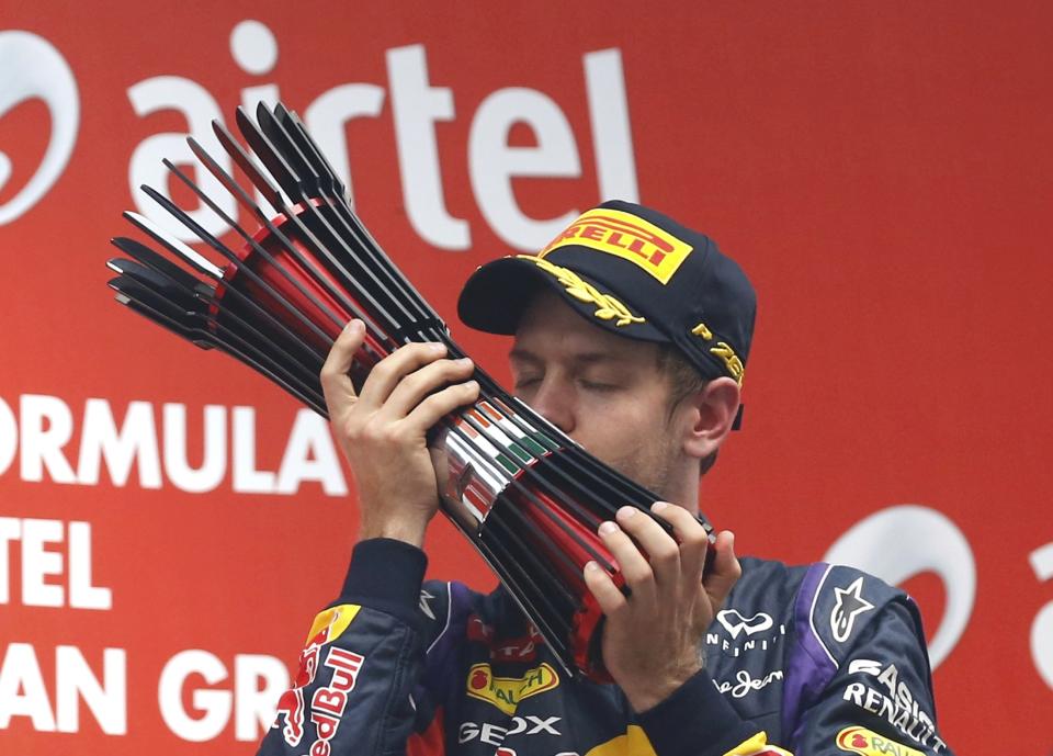 Red Bull Formula One driver Sebastian Vettel of Germany kisses his trophy on the podium after winning the Indian F1 Grand Prix at the Buddh International Circuit in Greater Noida, on the outskirts of New Delhi, October 27, 2013. Vettel became Formula One's youngest four-times world champion on Sunday after winning the Indian Grand Prix for Red Bull. Red Bull also took the constructors' championship for the fourth year in a row. The victory from pole position was the 26-year-old's sixth in a row and completed a hat-trick of wins in India where no other driver has ever won since the race made its debut in 2011. REUTERS/Ahmad Masood (INDIA - Tags: SPORT MOTORSPORT F1)